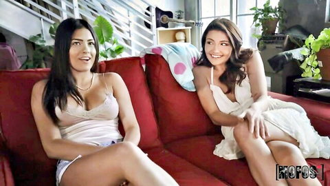 Two cute Latina teen girls smiling in tank top and dress on couch