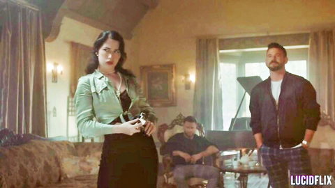 Octavia Red in sexy green jacket and black skirt holding camera with two men