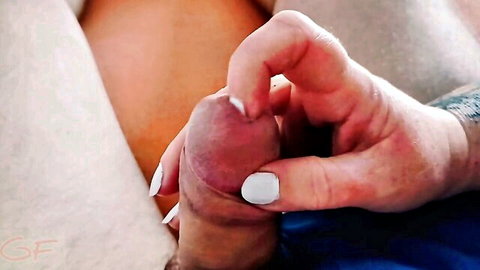 Close-up of woman's tattooed hand with white nails gripping stepson's erect penis