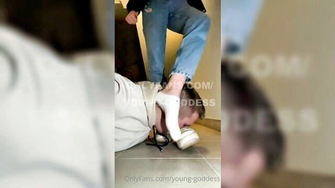 Young femdom mistress in white socks tramples humiliated slave's face on floor
