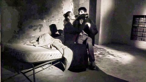 Selen De Rosa in vintage 1995 scene, passionate kiss with man holding prop, black and white