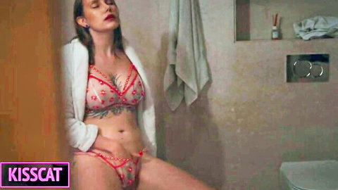 Busty MILF in open blazer and red lace lingerie spreads legs wide in bathroom teasing big tits