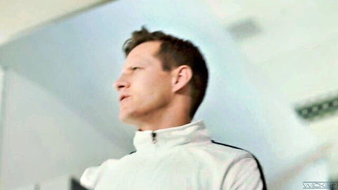 Handsome man in white track jacket profiles sideways in locker room