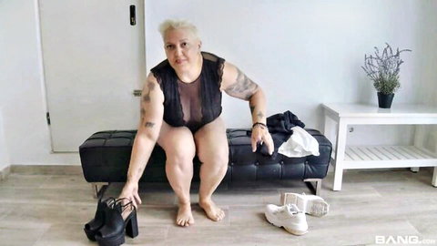 Mature blonde Nuria Madura in sheer black lingerie, short hair, tattoos, teasing pose