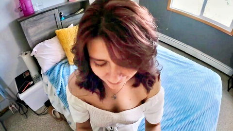 Smiling redhead in white off-shoulder top teases cleavage close-up