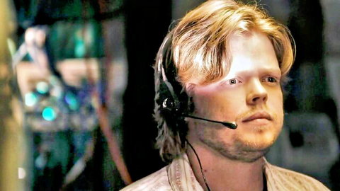 Blonde man with headset in dimly lit studio, Paula Patton reference