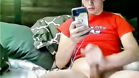 Slim black-haired guy in red shirt masturbates to phone porn solo