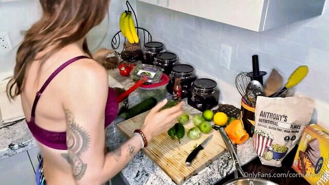 Tattooed brunette in lingerie chops veggies in kitchen tease