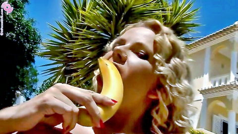 Blonde curly-haired woman sensually eating banana outdoors