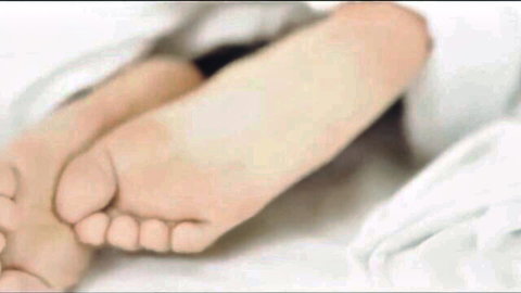 Sexy pale bare feet and soles peeking from white sheets on bed foot fetish tease