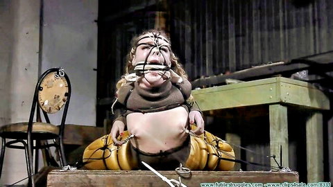 Plump gagged woman tightly bound in ropes and chains exposing belly in BDSM restraint