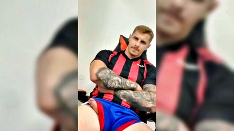 Blond muscular man with tattoos exposing large cock in blue shorts