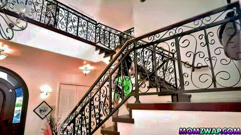 Sexy stepmom in tight green dress posing on grand staircase