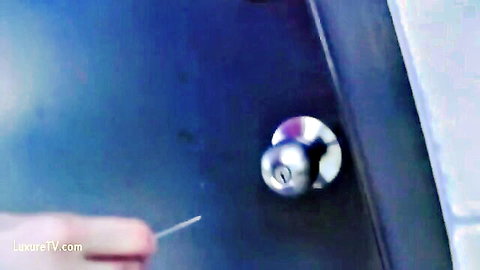 Hand inserting thin wire pin into silver door keyhole lock for picking
