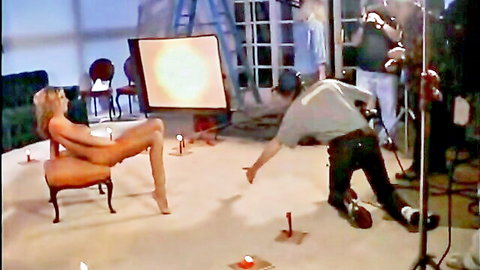 Blonde nude model on adult film set with crew filming explicit scene