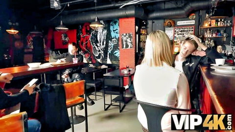 Blonde woman in white top flirts with man at bar in cuckold scene