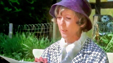 Vintage 1976 Danish film scene: mature blonde in polka-dot dress and hat outdoors