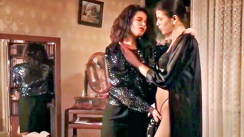 Two curvy brunettes in sparkly black top and robe share intimate bedroom embrace