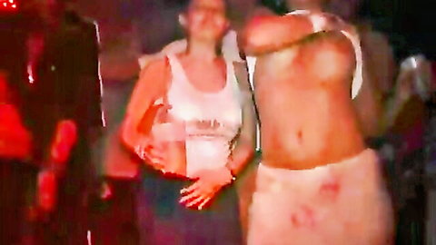 Brunette party girl lifts white tank top flashing underboob dancing with shirtless muscular hunk