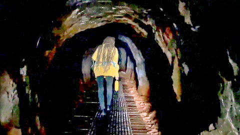 Implantboy walking into dark tunnel in yellow top and jeans