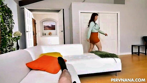 Syren De Mer in green top and red mini skirt approaching exposed man on couch