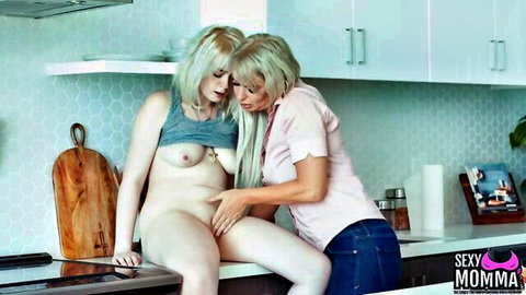 Blonde woman fingers shaved pussy of topless blonde on kitchen counter