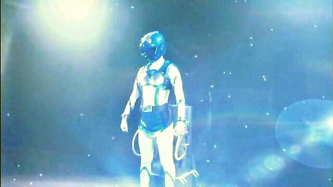 Futuristic sci-fi woman in tight blue spacesuit and helmet posing in starry space