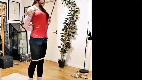 Brunette submissive bound arms overhead in rope shibari predicament bondage red top black leggings solo