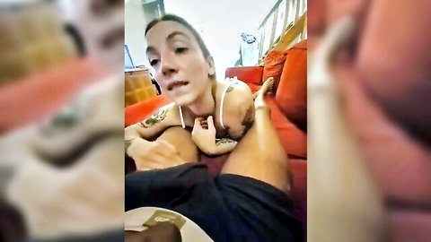 Tattooed white woman in tank top spreads legs as black man's hand grips her inner thigh on couch