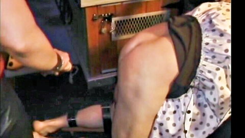 Submissive woman in polka dot dress restrained by wrists, exposed ass in BDSM scene
