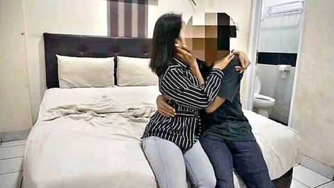Asian couple in intimate embrace, woman hugging man from behind on bed