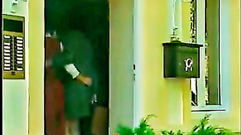 Two women embracing intimately at door in green and red dresses