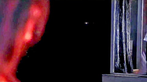 Blurry red silhouette peeking at lit window through dark curtains in Sasur Harami E01