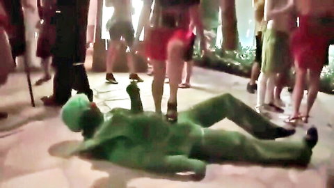Women in red dresses trampling costumed man in Halloween fetish scene