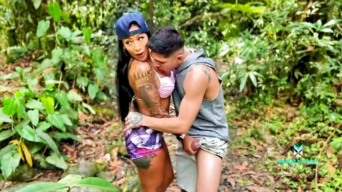 Mariana Martix tattooed Latina embracing man in jungle outdoor scene