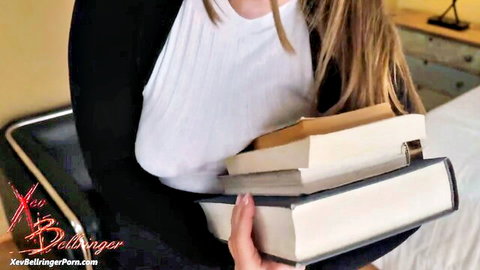 Xev Bellringer as busty blonde bimbo in cardigan and top holding books