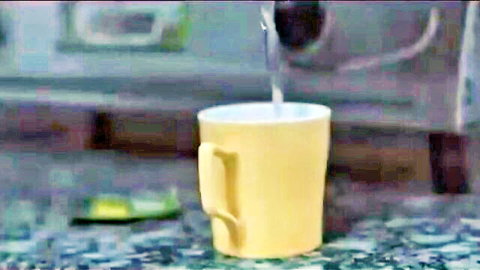 Yellow mug with spoon on green table, no nudity or sex visible