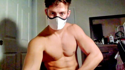 Muscular shirtless man in white mask teasing fitness pose