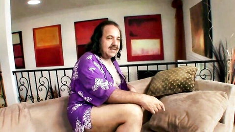 Hairy man in open purple kimono robe sits seductively on couch