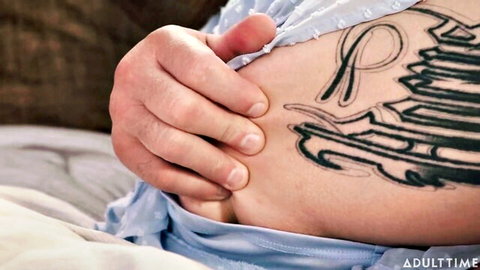 Man's hand grips tanned curvy woman's hip exposing bold tattoo under sheer lingerie
