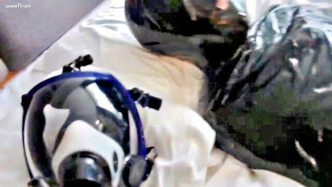Chinese woman in bondage restraint with blue gas mask on bed