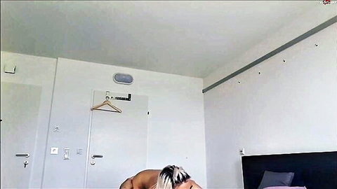 Naked blonde with black streaks bent over bed exposing bare ass from behind