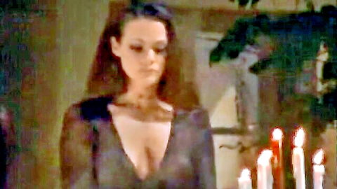 Mysterious brunette in sheer black dress with deep cleavage in candlelit ritual