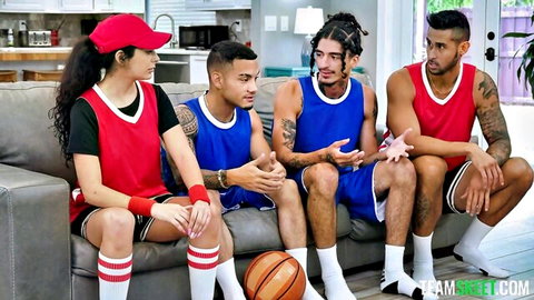 Brunette Latina teen in tight red basketball uniform sitting with three tanned muscular studs on couch