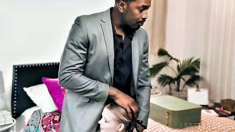 Petite blonde Coco Lovelock with suited black man in intimate bedroom pose