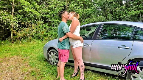 Blonde MILF passionately kissing hunk outdoors by silver car