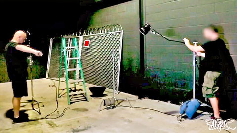 Behind the scenes crew setting up camera and lights at night outdoor fence location