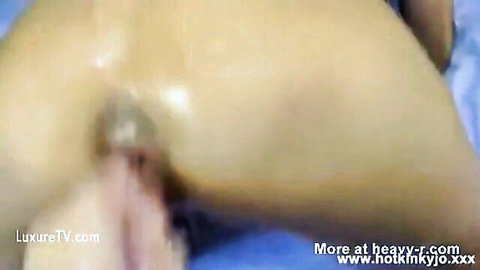 Extreme fisting close-up of woman with hand insertion in vagina on blue sheets