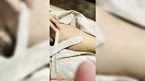 Blurry closeup of woman's pale thigh and hip exposed from open light robe with hand touching skin