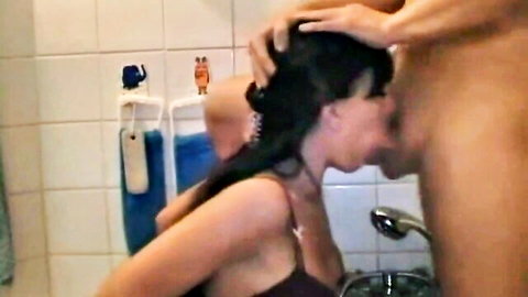 Brunette woman deepthroats man's cock as he grips her head forcefully in bathroom shower